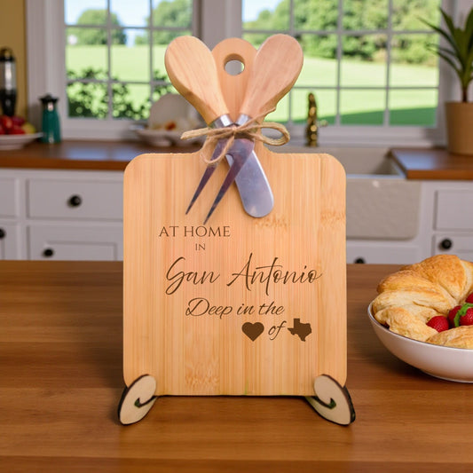 Bamboo charcuterie board engraved with “At Home in San Antonio, Deep in the Heart of Texas” displayed on a dining room table with warm décor accents.