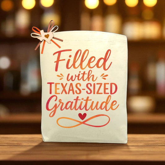 Canvas tote bag with the phrase “Filled with Texas-Sized Gratitude,” decorated with a bow, displayed on a wooden table in a warm gift setting.