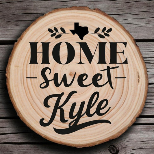 Rustic wood slice coaster with “Home Sweet Kyle” laser engraving, Texas silhouette, and leafy accents on wood background.