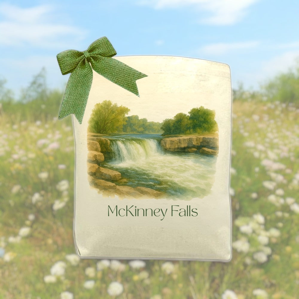 McKinney Falls tote bag with watercolor design and green ribbon, featuring scenic Texas waterfall illustration