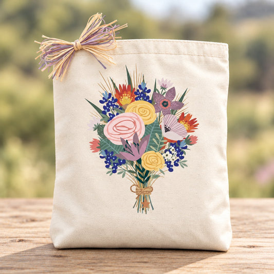 Texas Wildflower Bouquet canvas gift tote with a colorful floral design and natural lavender raffia on a wood tabletop