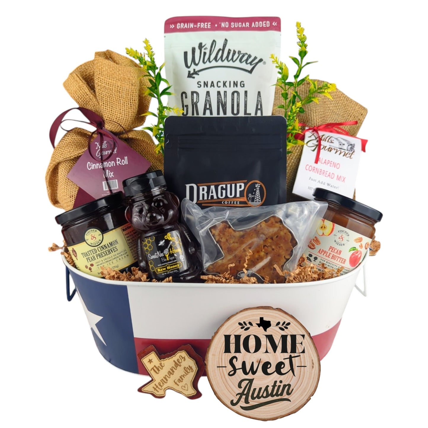 Austin Home Breakfast Basket on a plain white background, showing coffee, granola, cinnamon rolls, jalapeño cornbread mix, pecan apple butter, honey, and praline.