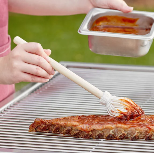 backyard pro bbq mop being put to use on a rack of ribs spreading bbq sauce