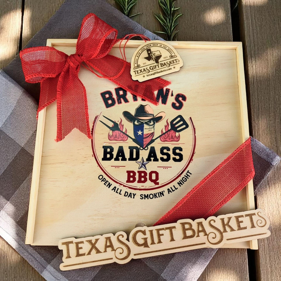 a wood gift box with "Bryan's BAD ASS BBQ" logo on the lid, and a red bow and Texas Gift Baskets tag