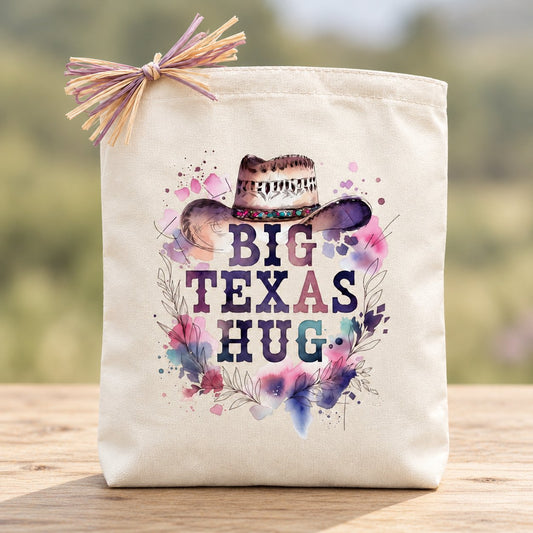 Big Texas Hug Cowgirl Edition gift tote with cowgirl hat and watercolor flowers, raffia bow and minimal natural setting