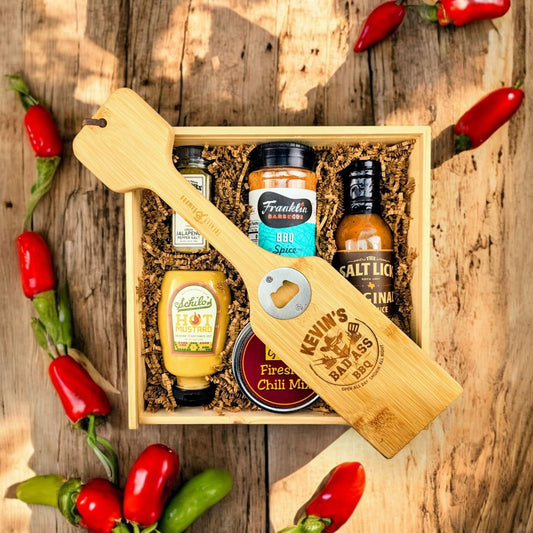 Wooden gift box packed with Texas-crafted BBQ essentials, featuring pepper salt, BBQ spice rub, BBQ sauce, mustard, and custom scraper