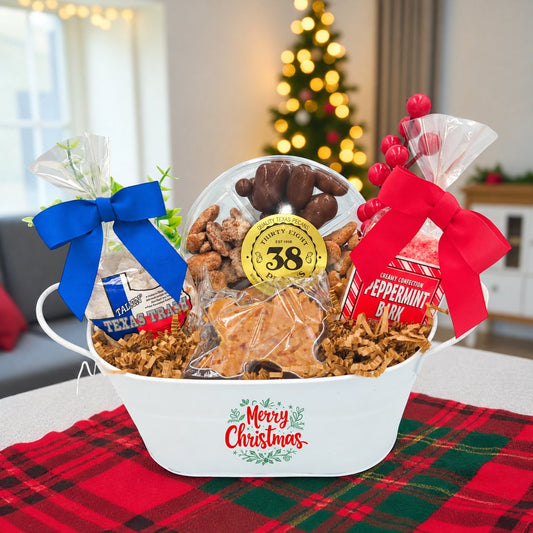 Texas Christmas Cheer Basket with Texas snacks, red and blue bows, and a Merry Christmas white basket in a softly lit holiday setting