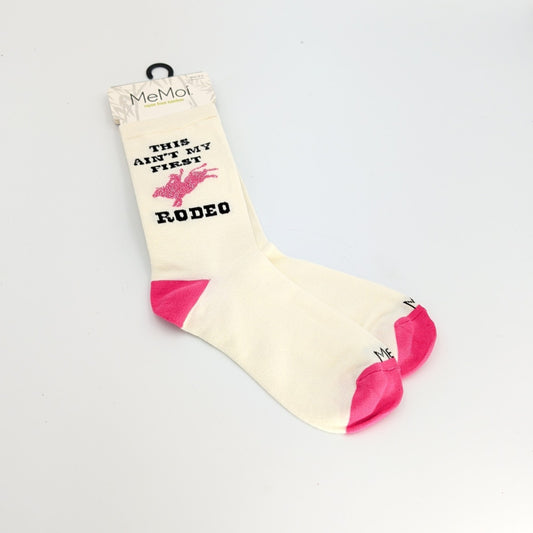 Cream-colored bamboo blend crew socks with pink heel and toe accents, featuring the phrase “This Ain’t My First Rodeo” and a pink rodeo graphic, displayed on a white background.