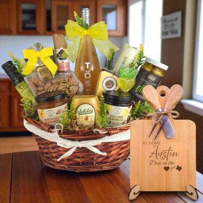 A beautifully arranged gourmet gift basket paired with the At Home in Austin Charcuterie Board, featuring bamboo wood, rustic utensils, and engraved Texas design, perfect for celebrating Austin’s vibrant spirit.