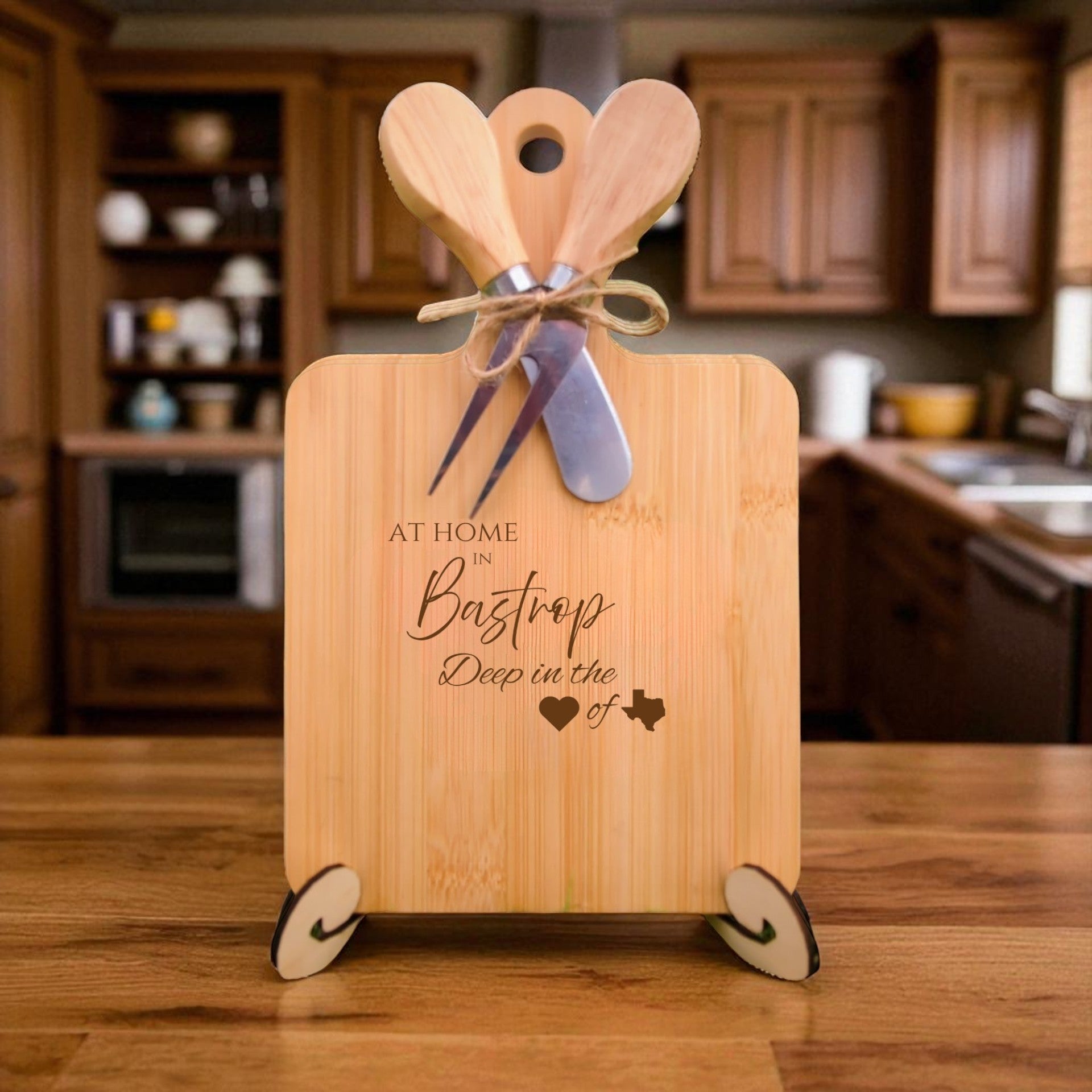 The At Home in Bastrop Charcuterie Board with laser-engraved Texas silhouette and “At Home in Bastrop” text, displayed in a cozy kitchen, ideal for entertaining and Texas pride.