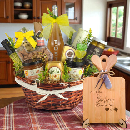 A gourmet gift basket paired with the At Home in Burleson Charcuterie Board, featuring bamboo wood, rustic utensils, and engraved Texas design, perfect for celebrating Burleson’s community spirit.