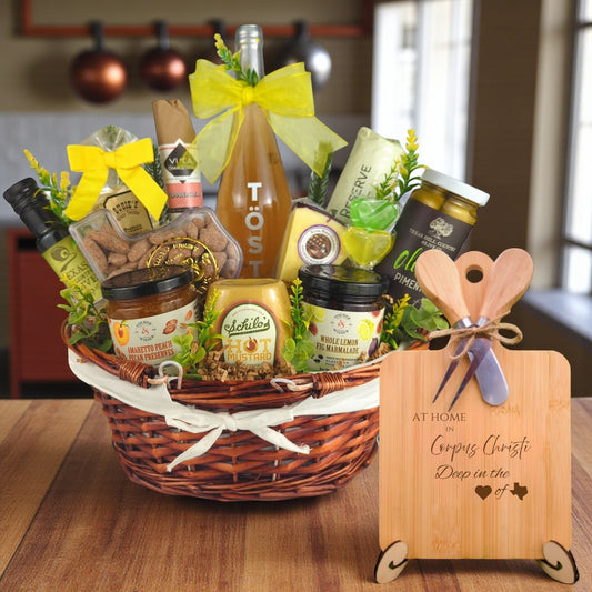 A gourmet gift basket paired with the At Home in Corpus Christi Charcuterie Board, featuring bamboo wood, rustic utensils, and engraved Texas design, perfect for celebrating Corpus Christi’s coastal charm.