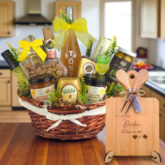A gourmet gift basket paired with the At Home in Denton Charcuterie Board, featuring bamboo wood, rustic utensils, and engraved Texas design, perfect for celebrating Denton’s vibrant community spirit.