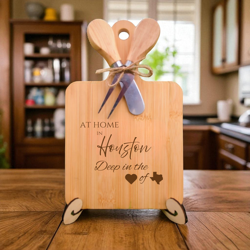 Bamboo charcuterie board engraved with “At Home in Houston, Deep in the Heart of Texas” displayed on a rustic wooden table in a kitchen setting.