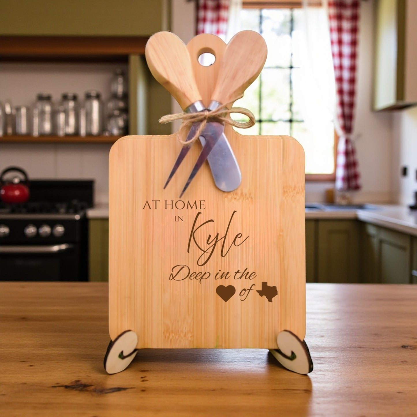 Bamboo charcuterie board engraved with “At Home in Kyle, Deep in the Heart of Texas” displayed on a kitchen counter with home décor in the background.