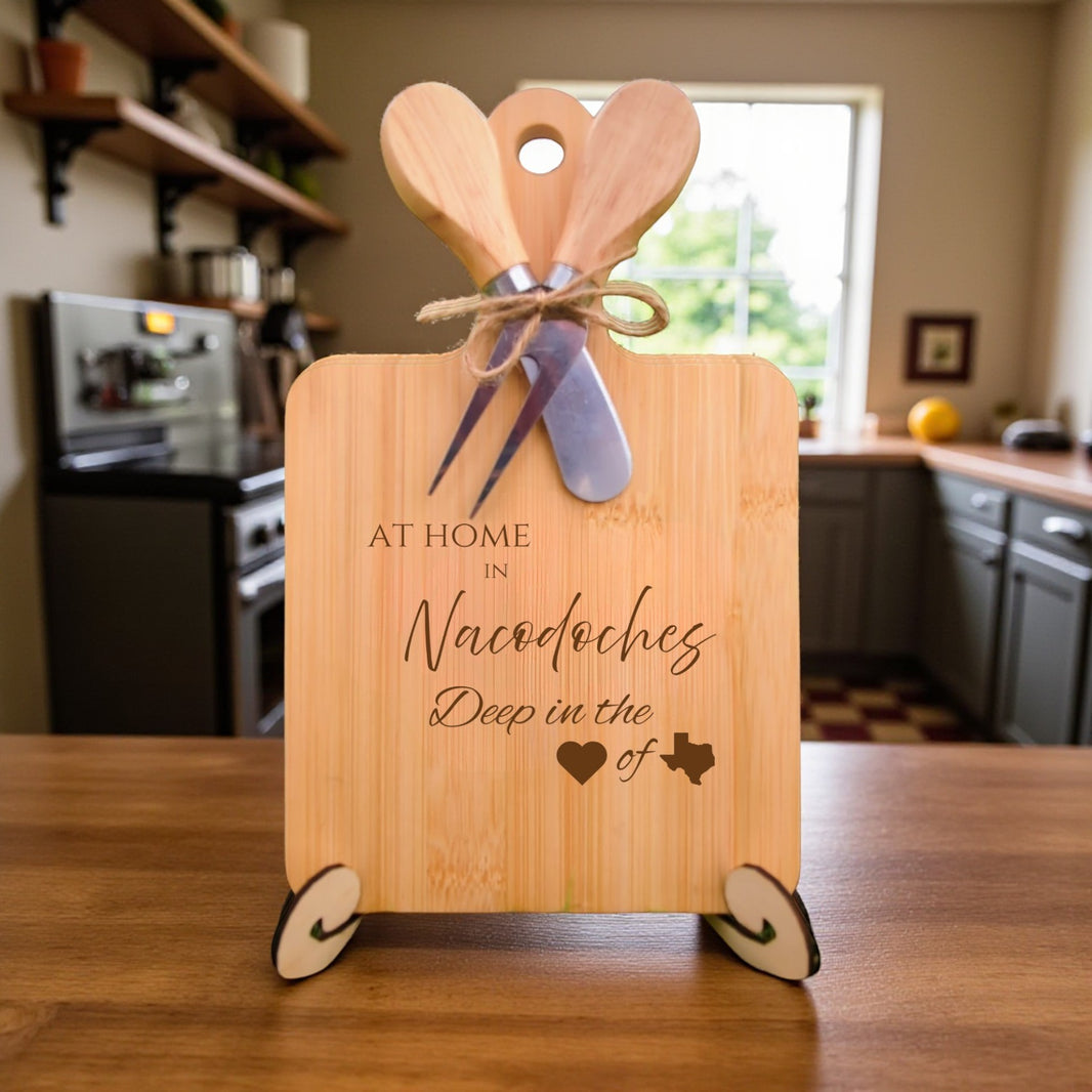 Bamboo charcuterie board engraved with “At Home in Nacogdoches, Deep in the Heart of Texas” displayed on a rustic table with kitchen décor.