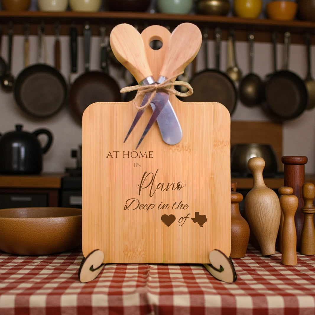 Bamboo charcuterie board engraved with “At Home in Plano, Deep in the Heart of Texas” displayed on a dining table with kitchen décor.