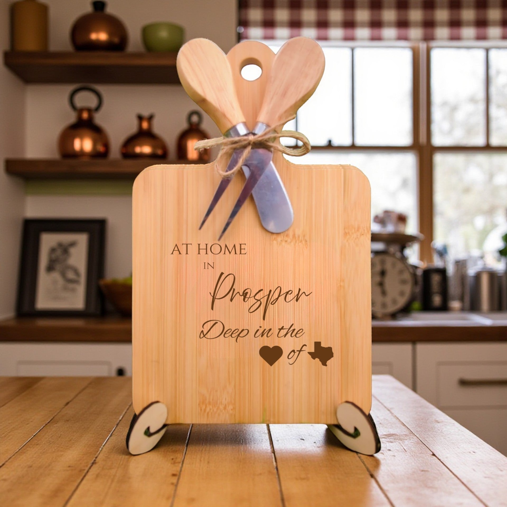 Bamboo charcuterie board engraved with “At Home in Prosper, Deep in the Heart of Texas” displayed on a kitchen counter with rustic décor.