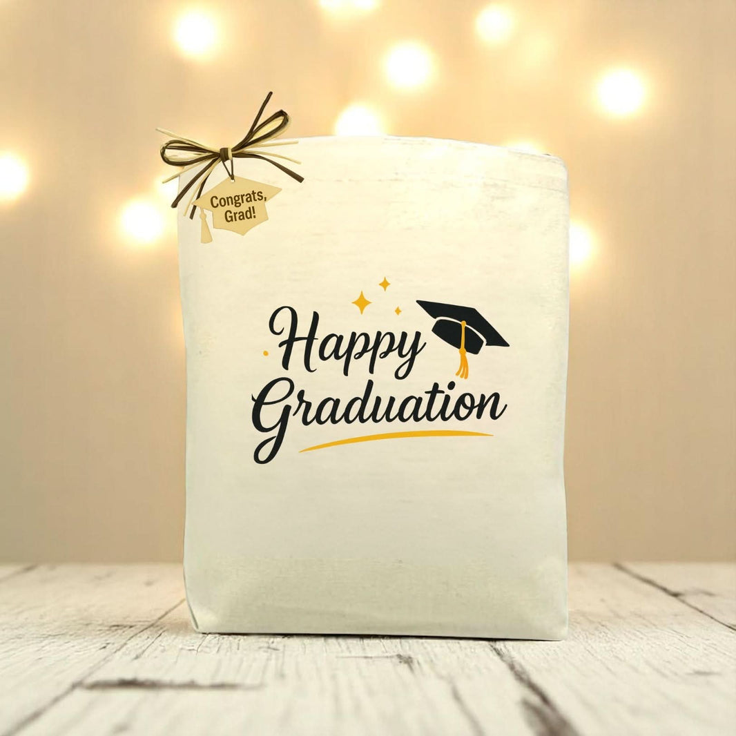 A white canvas tote bag with 'Happy Graduation' text and a graduation cap illustration, tied with a string.