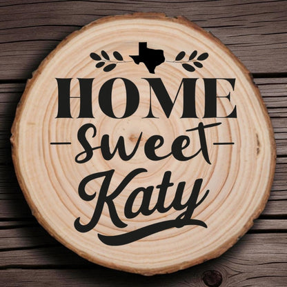 Rustic wood slice coaster with “Home Sweet Katy” laser engraving, Texas silhouette, and leafy accents on wood background