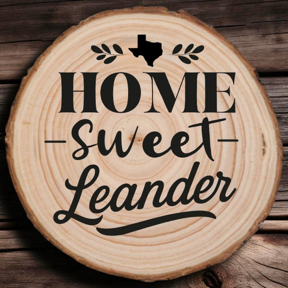 Rustic wood slice coaster with “Home Sweet Leander” laser engraving, Texas silhouette, and leafy accents on wood background.