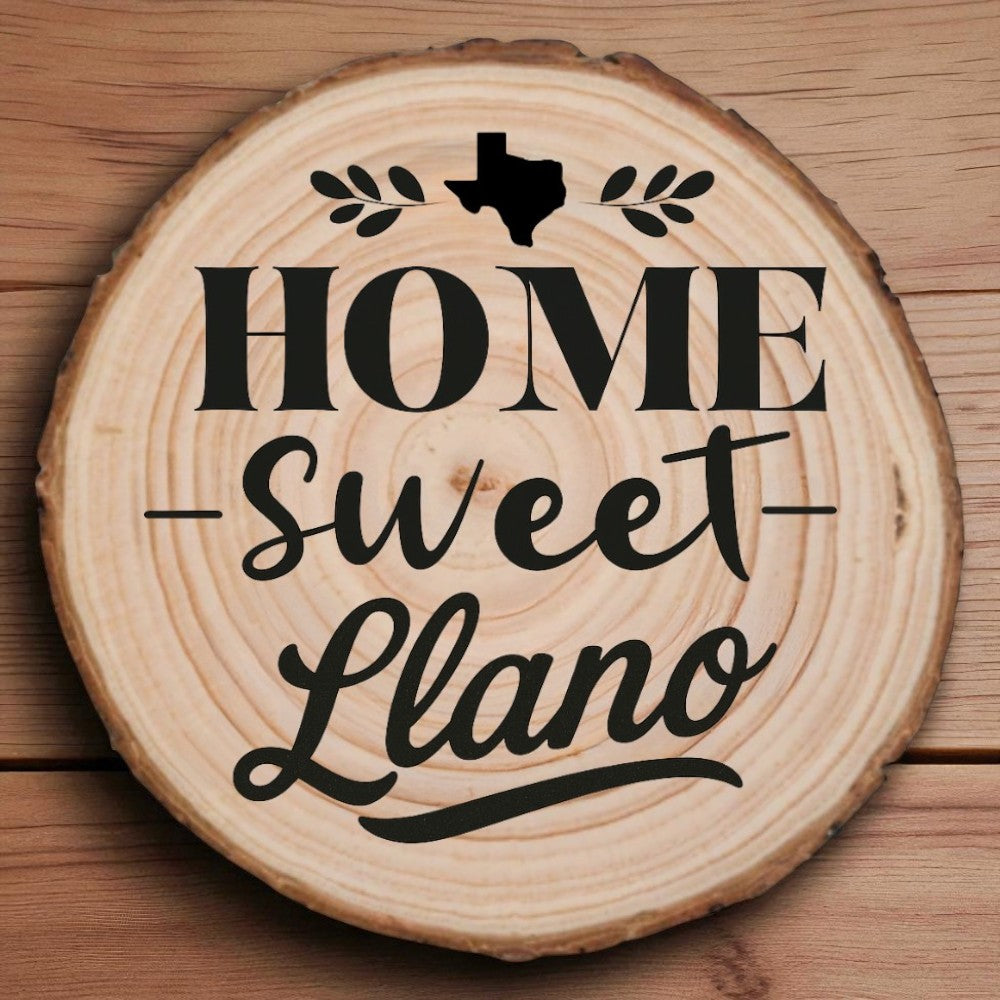 Rustic wood slice coaster with “Home Sweet Llano” laser engraving, Texas silhouette, and leafy accents on wood background.