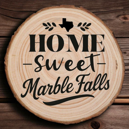 Rustic wood slice coaster with “Home Sweet Marble Falls” laser engraving, Texas silhouette, and leafy accents on wood background.