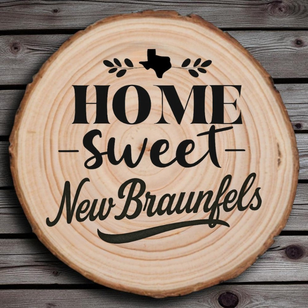 Rustic wood slice coaster with “Home Sweet New Braunfels” laser engraving, Texas silhouette, and leafy accents on wood background.