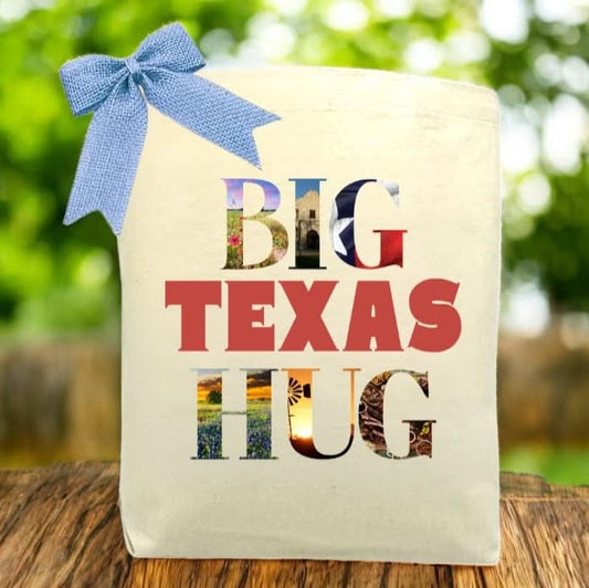 Big Texas Hug Tote filled with Texas-sourced sweets, snacks, seasonings, BBQ goods, and gourmet foods, presented as a customizable Texas gift basket on a rustic wooden surface.