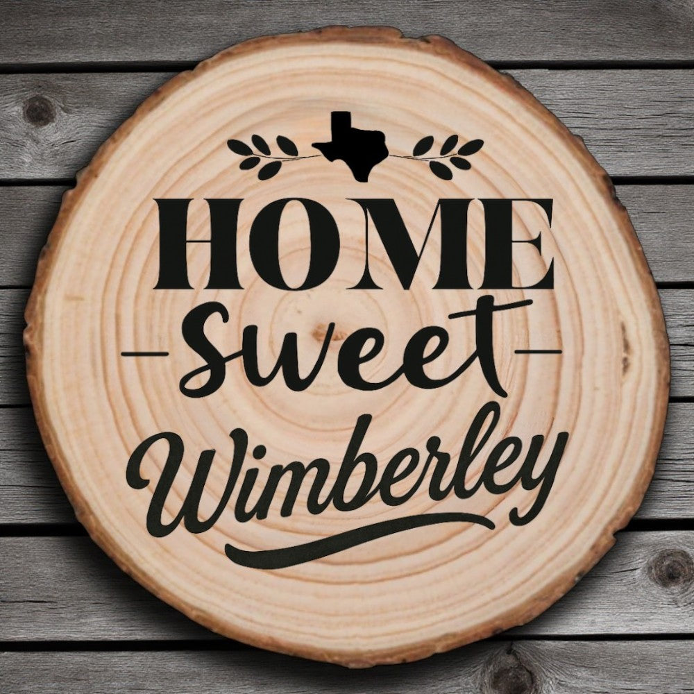 Rustic wood slice coaster with “Home Sweet Wimberley” laser engraving, Texas silhouette, and leafy accents on wood background.