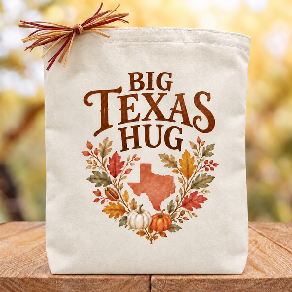 Cream canvas Big Texas Hug fall tote with autumn leaves, pumpkins, Texas artwork and a simple raffia accent.