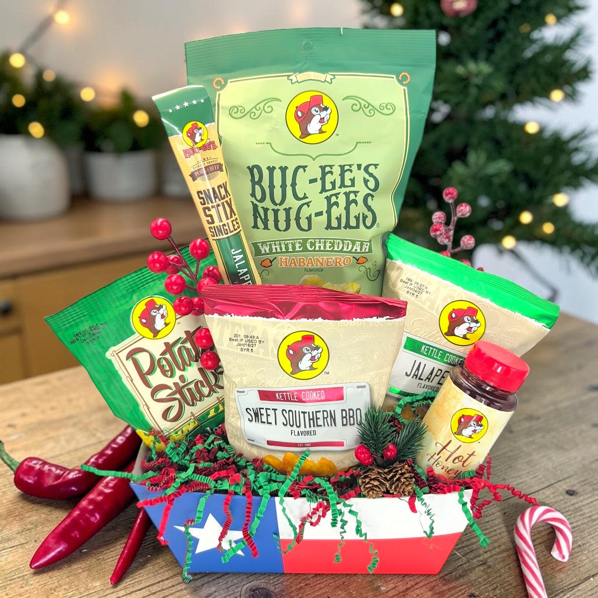Buc-ee’s Spicy Christmas Crunch, front-facing view in Texas flag tray; peppers and candy cane beside gift are photo props