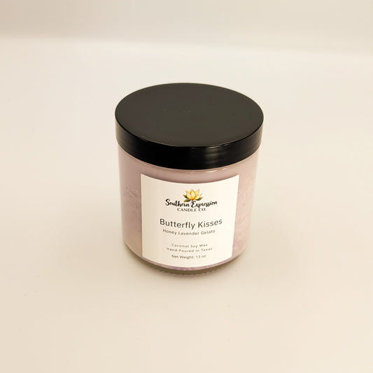 Lavender-colored glass jar candle with black lid labeled “Butterfly Kisses” by Southern Expression Candle Co., made with coconut soy wax and hand poured in Texas, displayed on a neutral background.