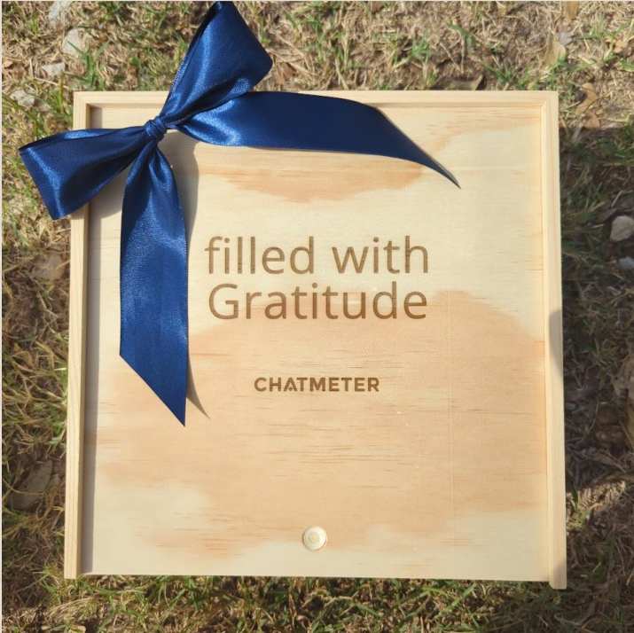 Engraved pine corporate gift box with navy ribbon and Chatmeter branding