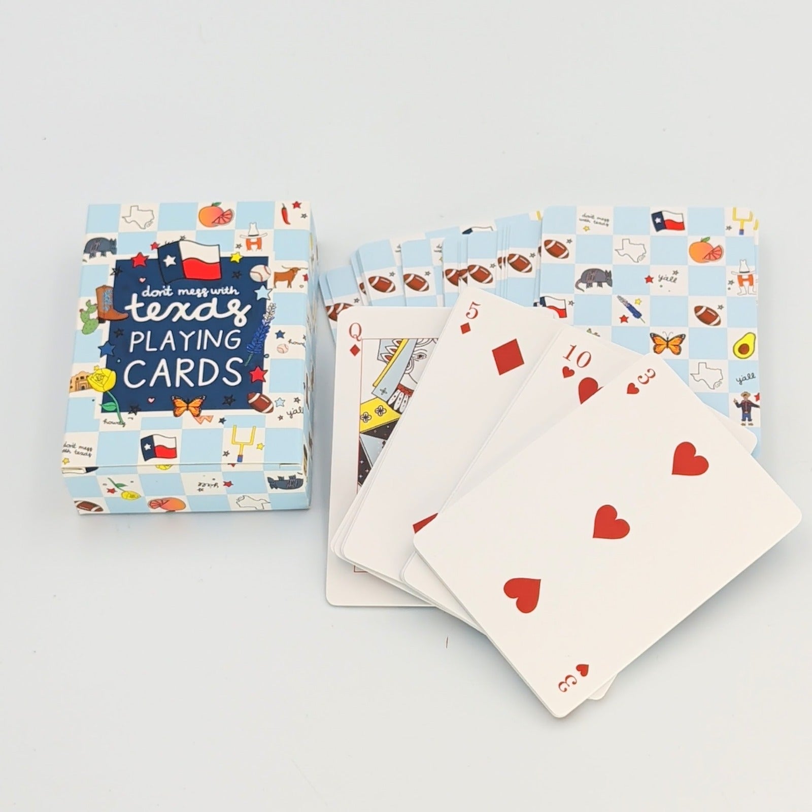 Texas-themed playing cards featuring a blue patterned deck with “Don’t Mess With Texas” design, shown with the box and a fan of heart and diamond suit cards on a white background.