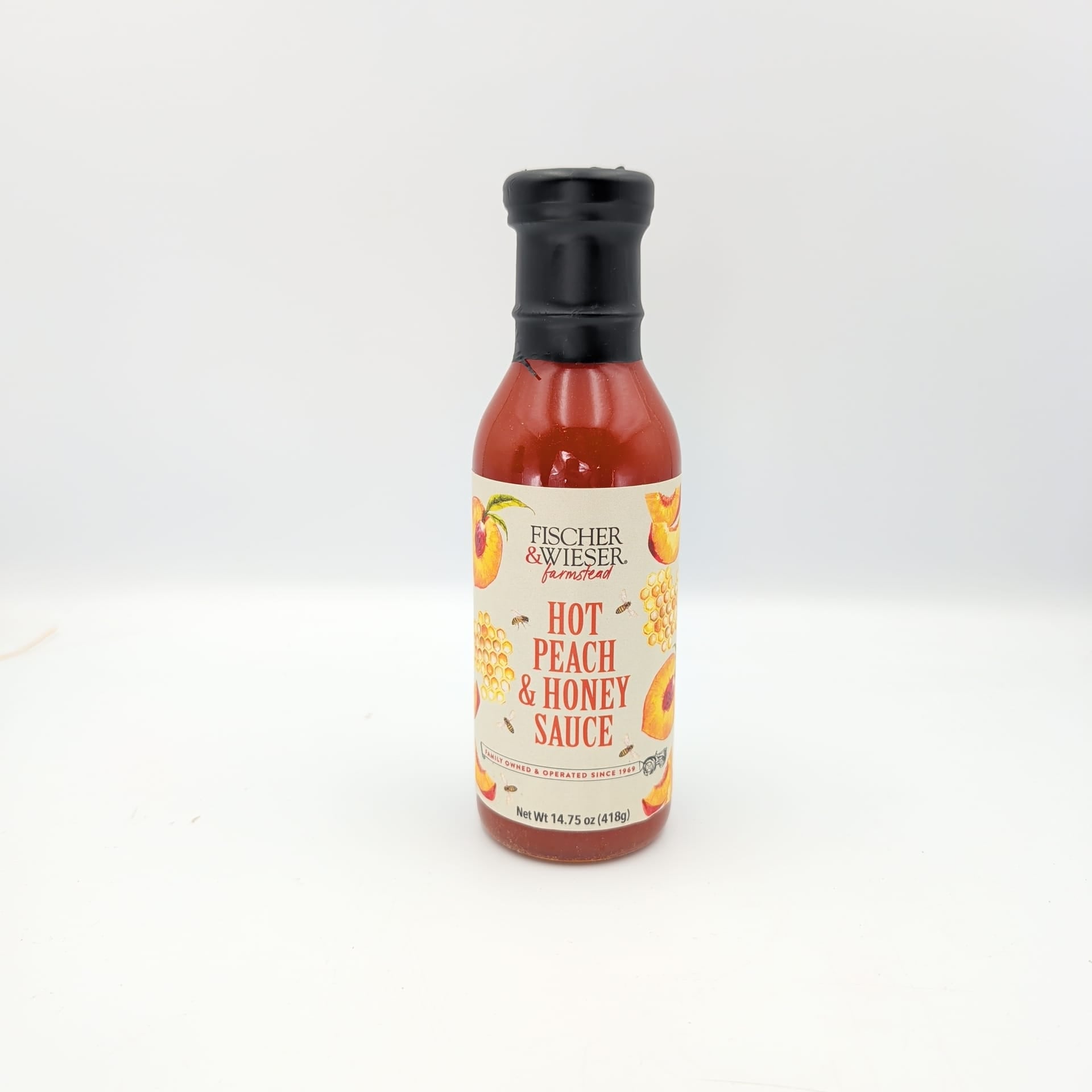Bottle of Fischer & Wieser Hot Peach & Honey Sauce with peach and honeycomb label artwork, displayed on a white background for gourmet Texas gift baskets and specialty food collections