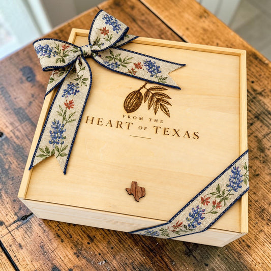 Wood gift box engraved with a pecan and leaves above From the Heart of Texas, tied with a bluebonnet ribbon