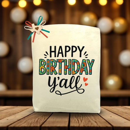 Happy Birthday Y’all canvas tote bag with festive Southern-inspired birthday design, displayed on a wooden table.
