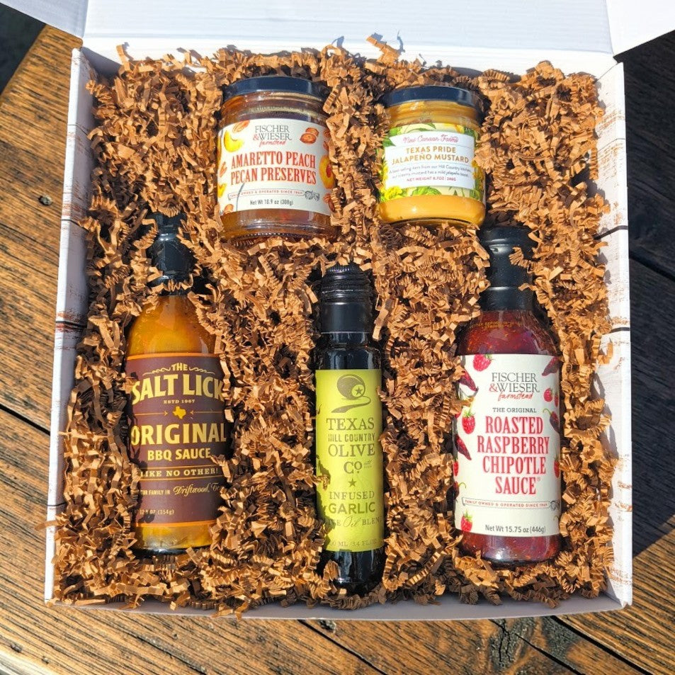 Hill Country Harvest Box open, showing Texas BBQ sauce, raspberry chipotle sauce, peach pecan preserves, garlic olive oil and jalapeno mustard in a distressed wood gift box