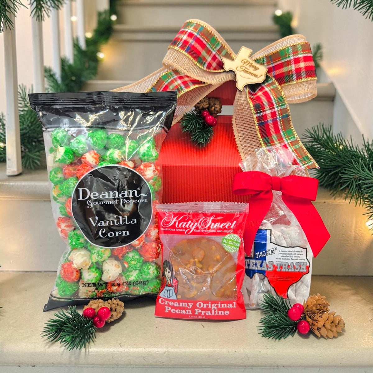 Merry Texmas Sweet Trio with holiday popcorn, pecan praline and Texas Trash beside a festive red gable box