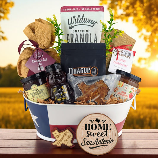 San Antonio Family Breakfast Basket with rustic outdoor background, Texas-themed tin filled with pecan coffee, cinnamon roll mix, jalapeño cornbread mix, granola, honey, praline, and preserves.