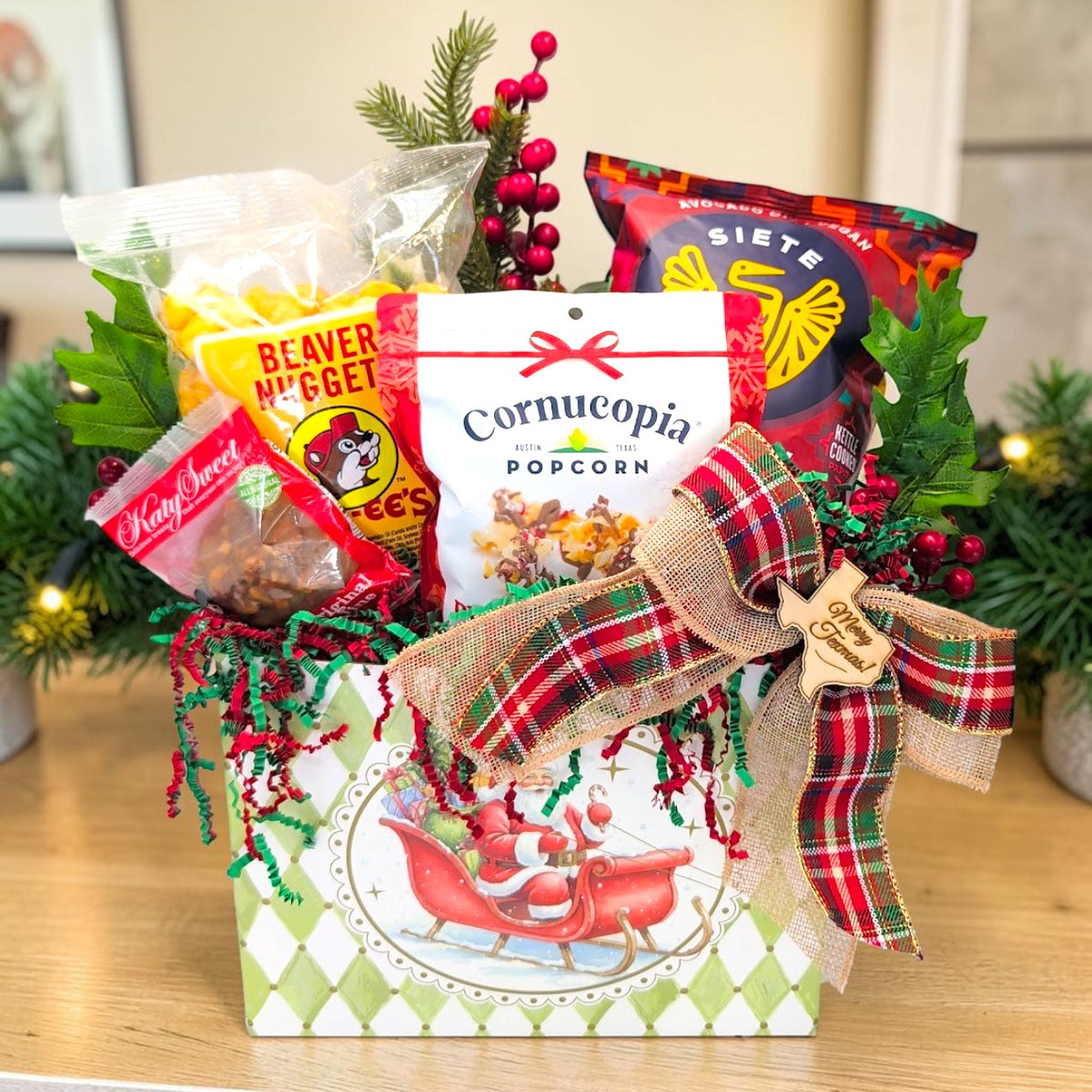 Santa’s Sweet Texas Quartet with four snacks, Christmas greenery and a plaid bow in a Jolly Santa basket box.
