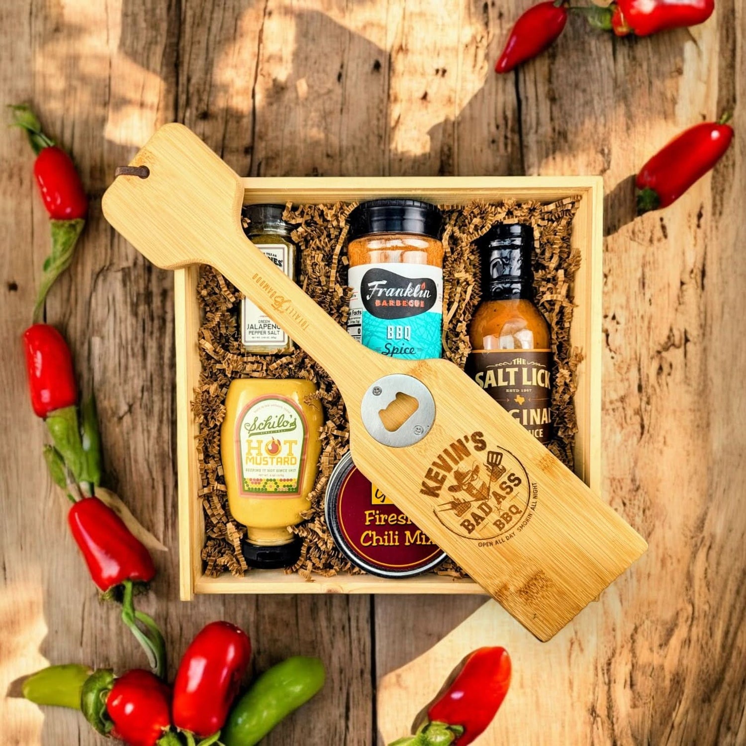 Wooden gift box packed with Texas-crafted BBQ essentials, featuring pepper salt, BBQ spice rub, BBQ sauce, mustard, and custom scraper