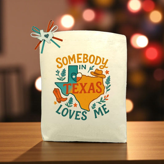 Canvas tote bag with Texas map and the phrase “Somebody in Texas Loves Me,” decorated with cowboy boots, hat, and floral accents
