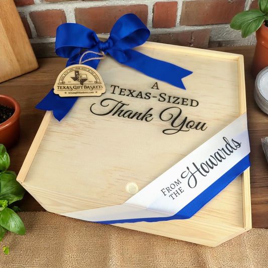 a wooden gift box with a texas gift baskets tag and "a texas-sized thank you" engraved on the lid, with custom printed ribbon that says "from the Howards"